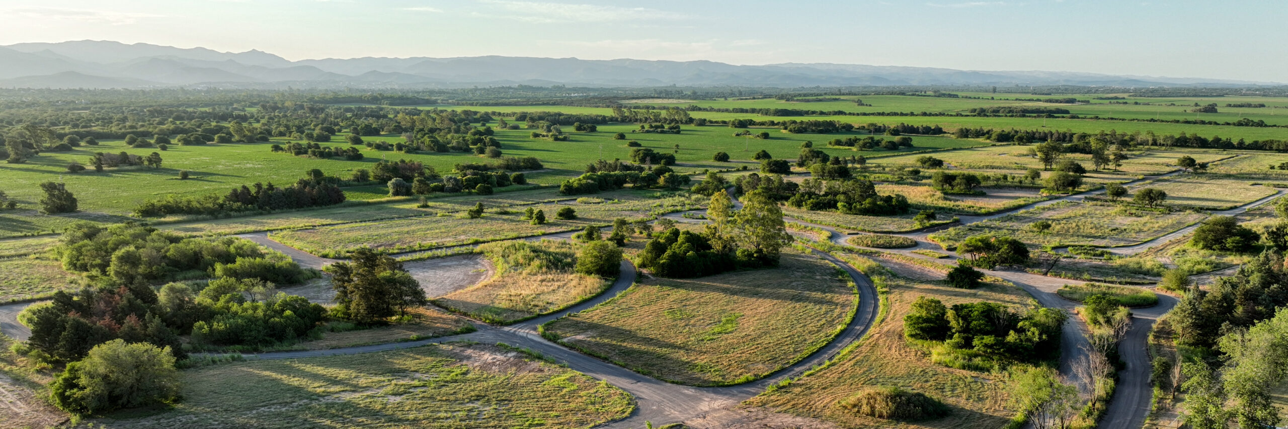 Vista aérea de Viarava con calles curvas, lotes amplios y vegetación integrada en un entorno natural de Sierras Chicas.