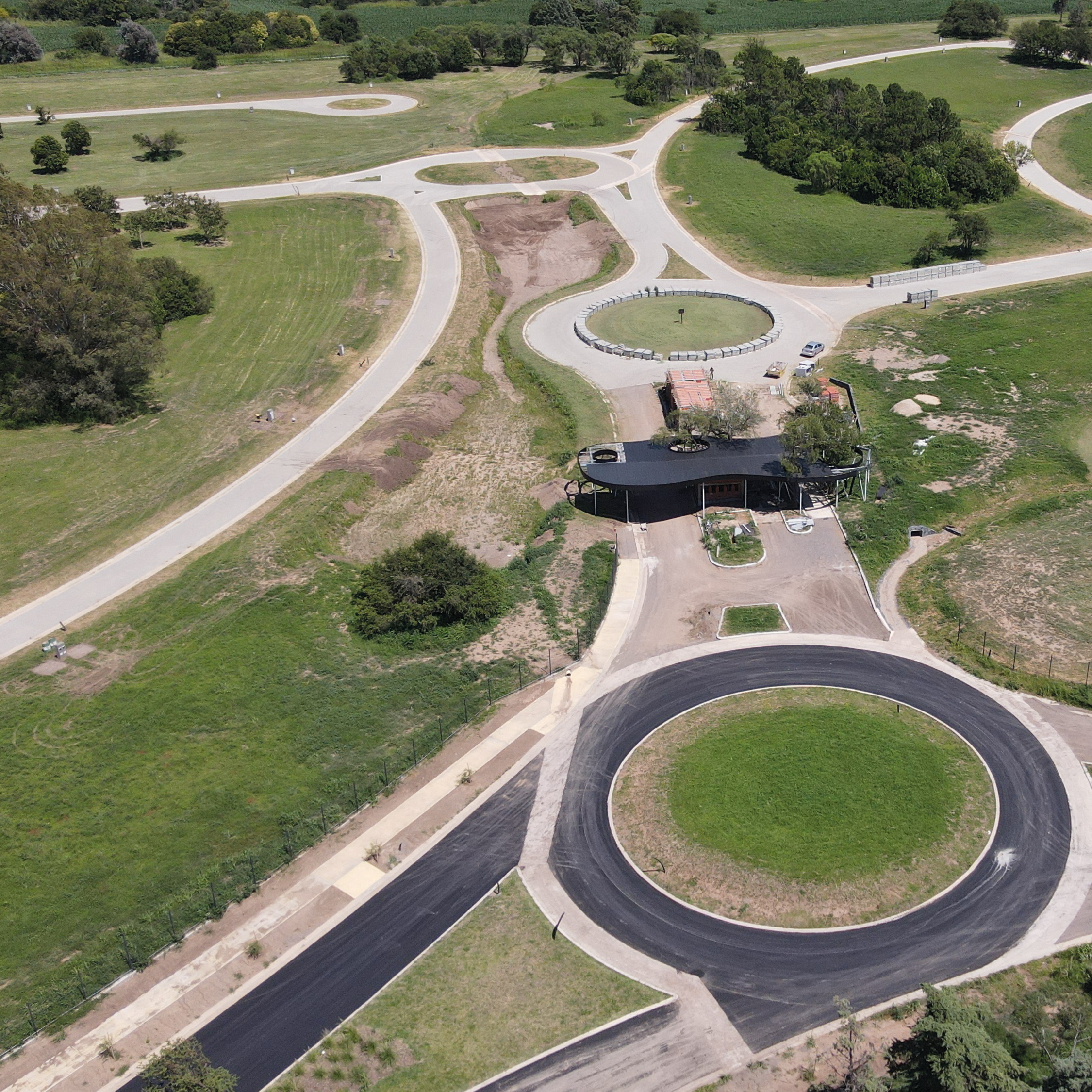 Vista aérea de calles internas en construcción en Viarava, con trazado curvo, vegetación natural y laguna integrada al paisaje.